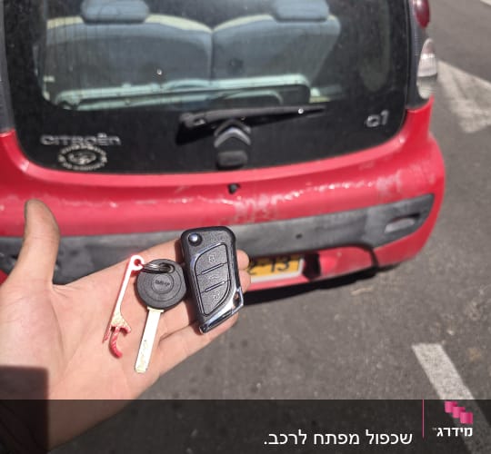 מפתח רכב ושלט מול מכונית אדומה